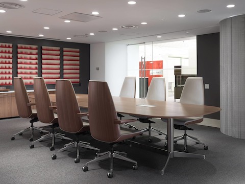 A meeting room featuring an oblong MP Conference Table and high-back Clamshell office chairs with veneer shells and ivory-colored leather upholstery.
