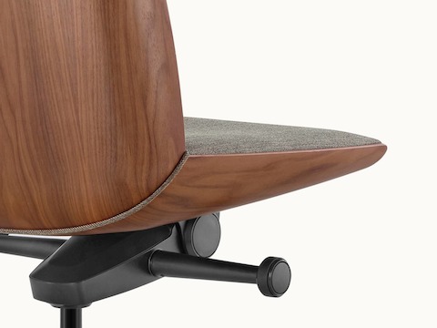 Angle view of a low-back Clamshell office chair with black leather upholstery, a walnut shell, with no arms.