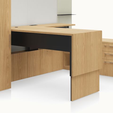 A close-up of a work station at standing height from Geiger One Casegoods featuring an exposed plywood edge, matte black leg, and disc foot.