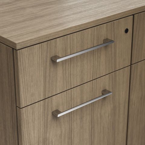 Detail shot of the Geiger One Casegoods bracket pull option in Chrome on a Natural Flat Cut Walnut drawer front viewed from an angle.