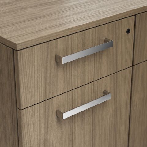 Detail shot of the Geiger One Casegoods channel pull option in Chrome on a Natural Flat Cut Walnut drawer front viewed from an angle.