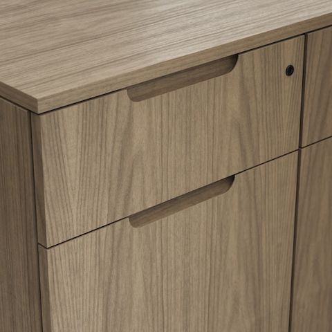 Detail shot of the Geiger One Casegoods partial wood flush pull option on a Natural Flat Cut Walnut drawer front viewed from an angle.