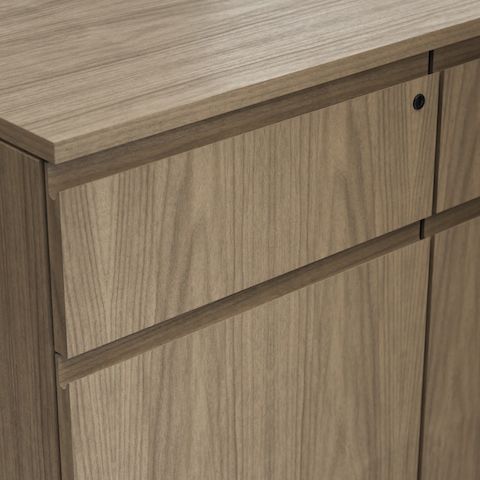 Detail shot of the Geiger One Casegoods solid wood flush pull option on a Natural Flat Cut Walnut drawer front viewed from an angle.