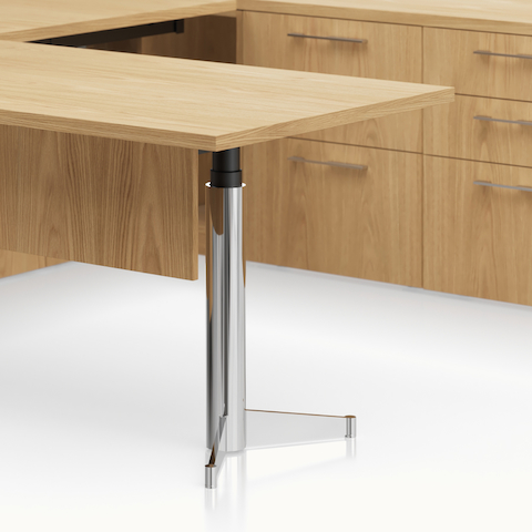 Detail shot of the Geiger One Casegoods MP leg option with a black interior and chrome outer base in a Natural Flat Cut Oak private office.
